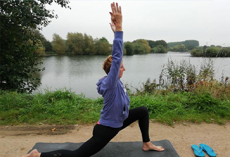 person doing yoga beside lake