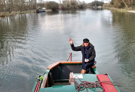 woman waves from tiller of narrowboat