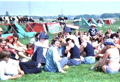 youngsters sitting on grass beside moored narrowboats